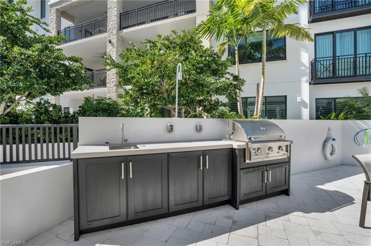 Outdoor kitchen featuring a built-in grill, integrated sink, and dark wood-finish cabinetry