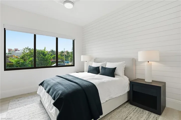 Expansive window with black framing, wood-finish flooring, shiplap accent wall, and a ceiling fan