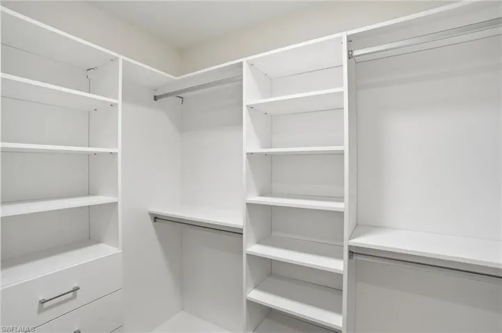 Custom built-in closet system with extensive shelving, hanging rods, and integrated drawers with contemporary hardware