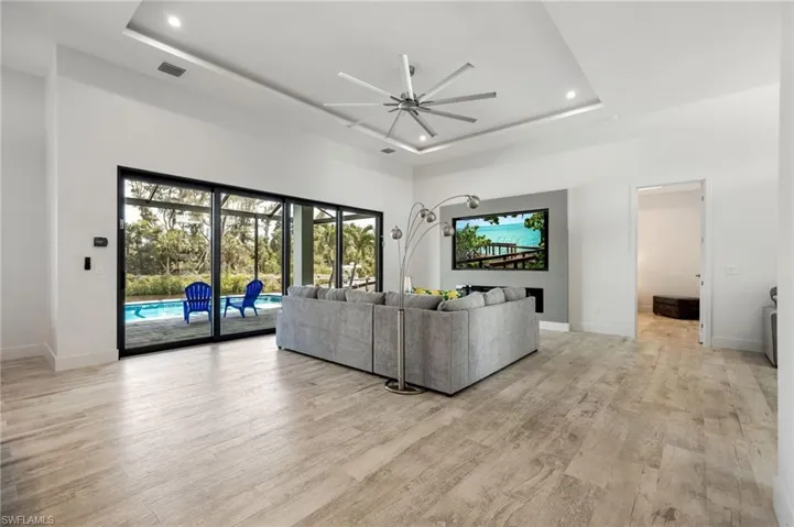Living area with ceiling fan, a raised ceiling, recessed lighting, healthy amount of natural light, and a high ceiling