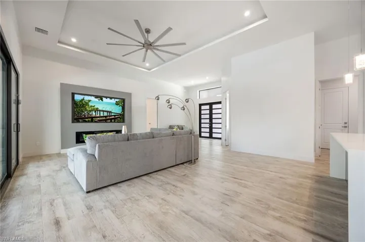 Living area featuring a tray ceiling, a ceiling fan, light wood-type flooring, and recessed lighting