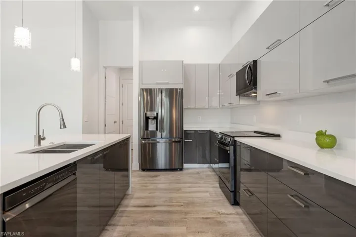 Kitchen featuring stainless steel fridge, dishwasher, range with electric stovetop, modern cabinets, and light wood-style floors