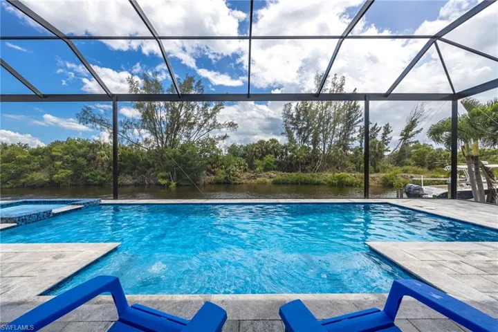 View of pool featuring a lanai, a water view, a pool with connected hot tub, and a patio area