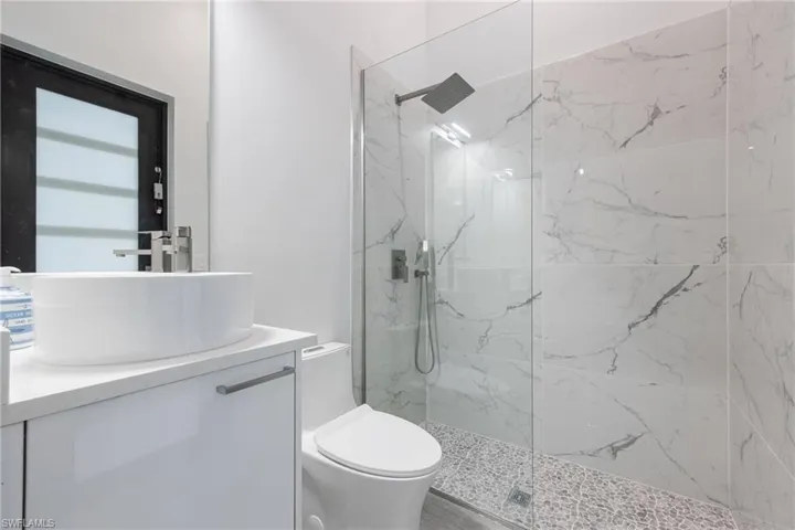 Bathroom with vanity and a marble finish shower