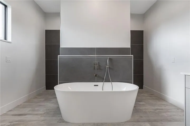 Bathroom featuring a freestanding tub, wood finished floors, and tile walls