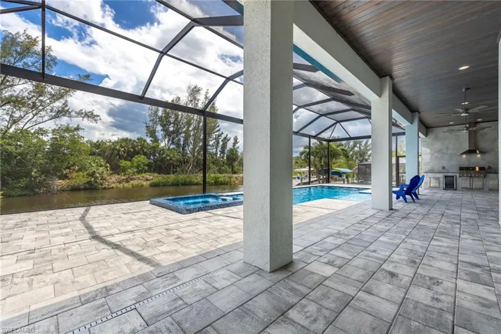 View of swimming pool featuring a patio, a ceiling fan, a lanai, a pool with connected hot tub, and an outdoor kitchen
