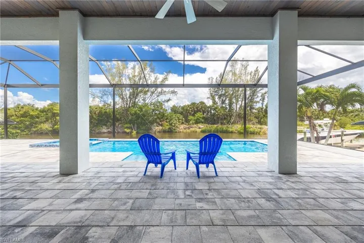 Outdoor pool with ceiling fan, a lanai, a patio, and view of wooded area