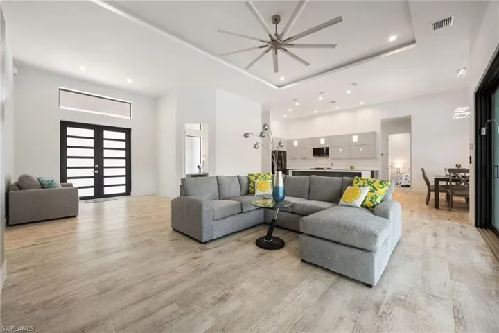 Living room with a high ceiling, light wood-style flooring, french doors, recessed lighting, and a ceiling fan