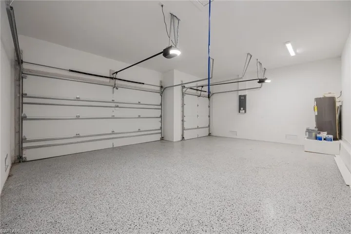 Garage featuring electric panel, a garage door opener, and water heater