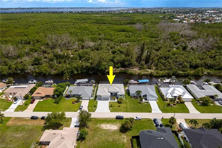 Aerial perspective of suburban area featuring a nearby body of water and a forest