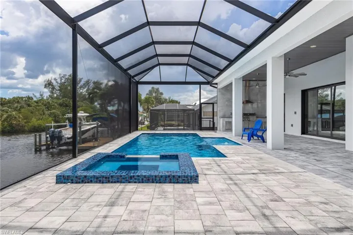 View of swimming pool with a patio, a pool with connected hot tub, glass enclosure, and ceiling fan
