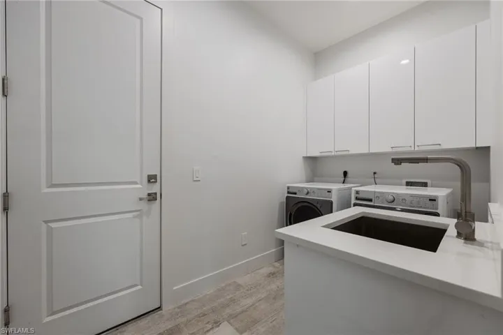 Washroom featuring cabinet space, independent washer and dryer, and light wood-style floors