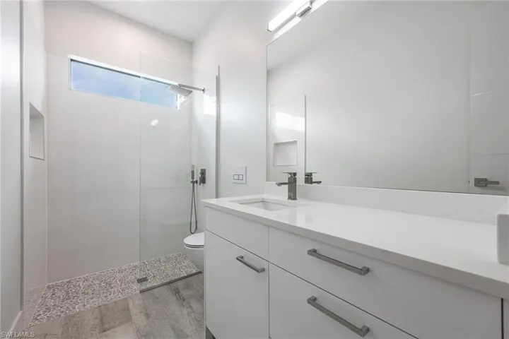 Bathroom with vanity, walk in shower, and wood finished floors