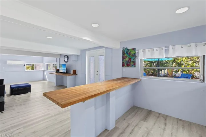 Kitchen with light wood-type flooring, a kitchen bar, an AC wall unit, butcher block countertops, and kitchen peninsula