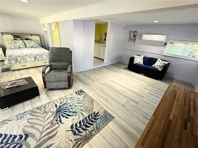 Bedroom with washing machine and clothes dryer and light hardwood / wood-style floors