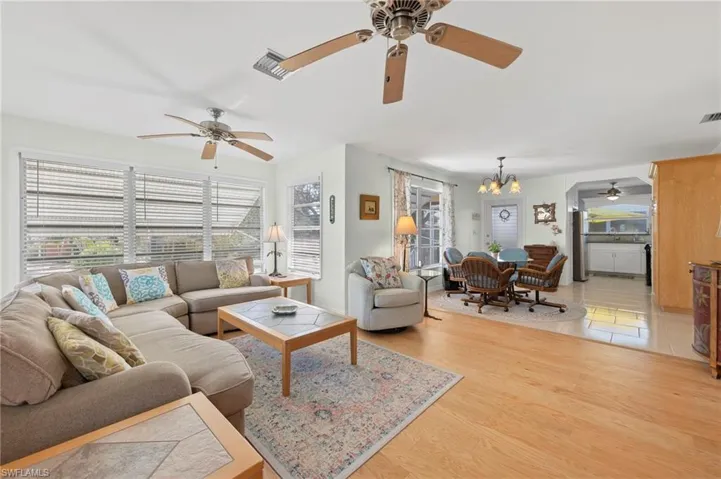 Tiled living room with ceiling fan with notable chandelier and a wealth of natural light