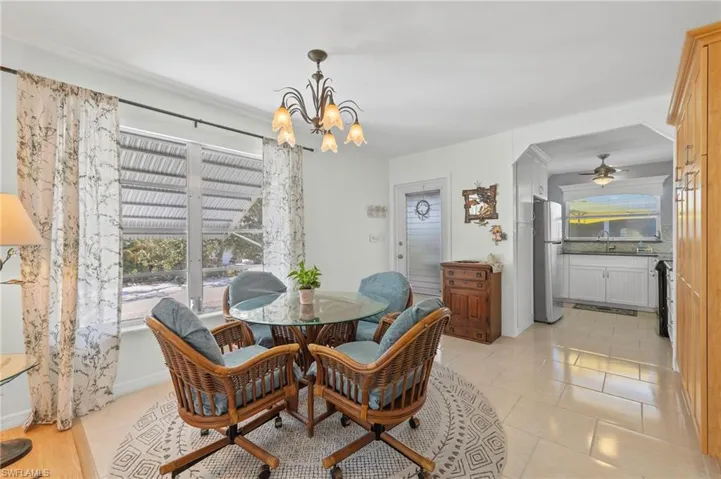 Dining area featuring light tile patterned floors and ceiling fan with notable chandelier