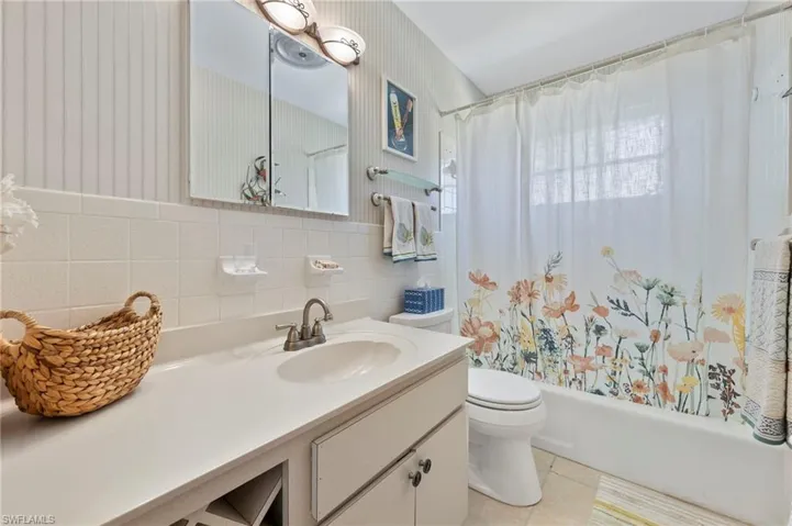 Full bathroom featuring toilet, tile walls, backsplash, tile patterned floors, and vanity