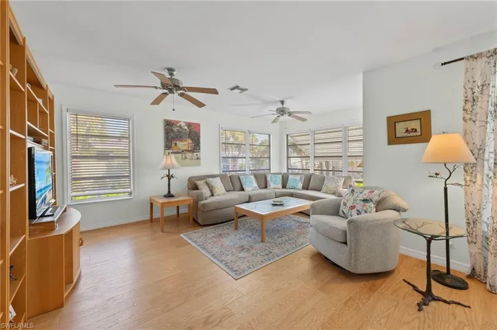 Living room featuring ceiling fan, light wood-type flooring, and a wealth of natural light