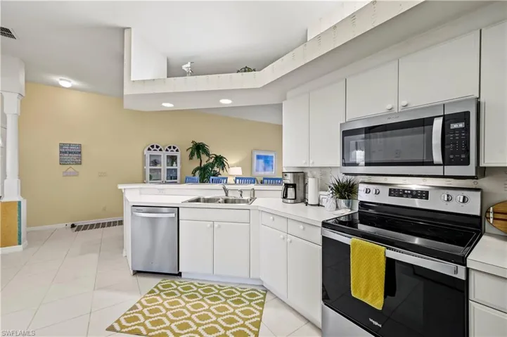 Kitchen featuring stainless steel appliances, white cabinetry, light tile patterned floors, sink, and kitchen peninsula