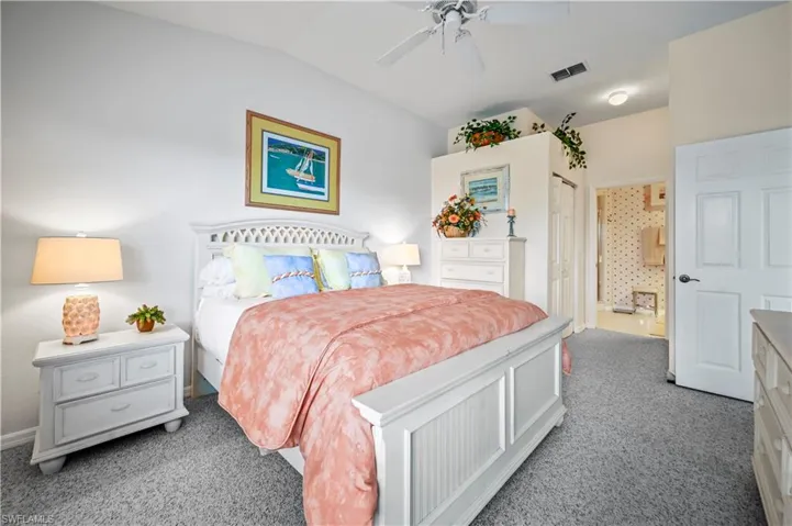 Carpeted bedroom with ensuite bathroom, lofted ceiling, and ceiling fan