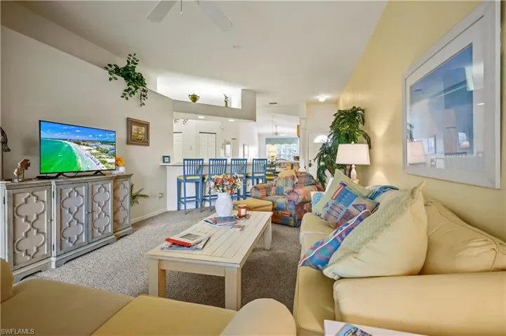 Living room with ceiling fan with notable chandelier and carpet floors
