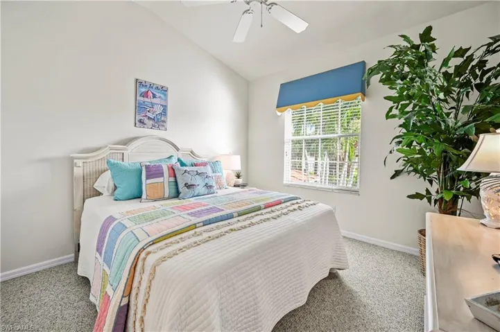 Carpeted bedroom with vaulted ceiling and ceiling fan