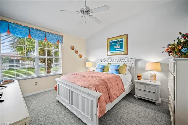 Bedroom with ceiling fan, lofted ceiling, and light colored carpet