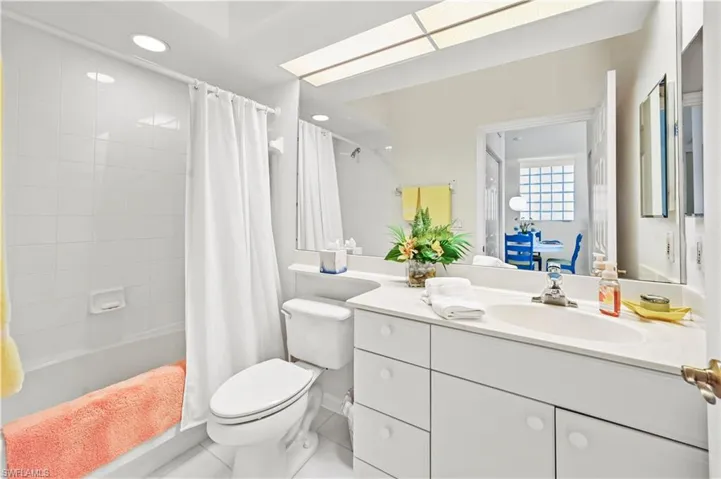 (This image has been virtually edited to show seller's recent removal of wallpaper in the guest bathroom) Full bathroom featuring tile patterned flooring, vanity, toilet, and shower / tub combo with curtain