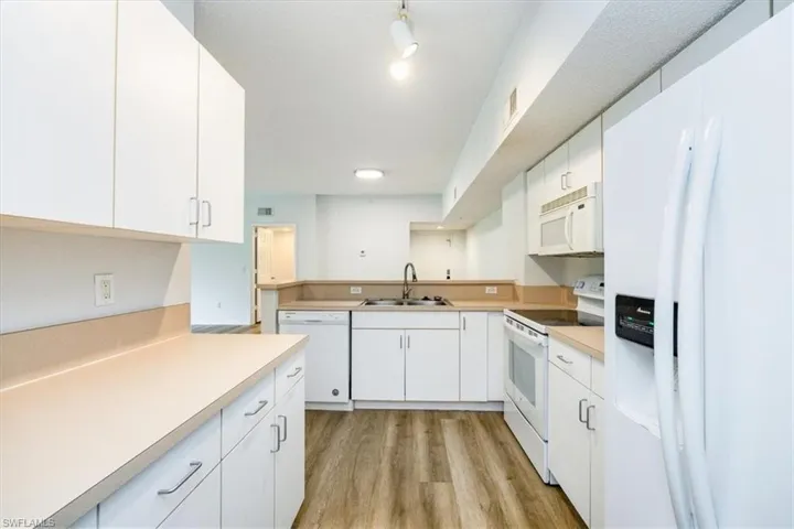 Kitchen featuring light wood-type flooring, white appliances, white cabinetry, and sink