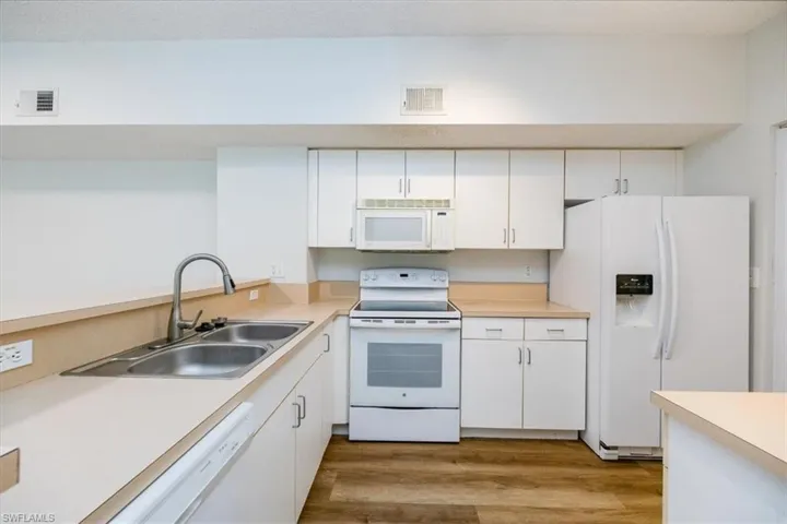 Kitchen featuring white cabinets, white appliances, sink, and hardwood / wood-style flooring