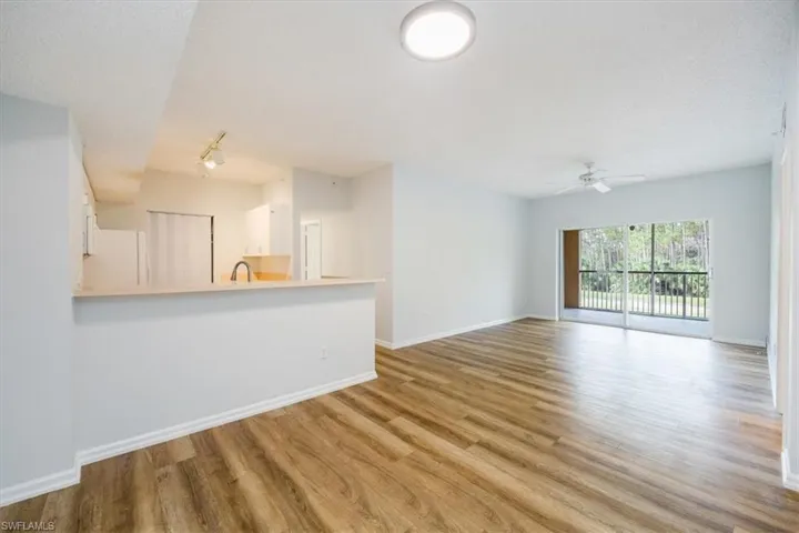 Unfurnished living room with ceiling fan, sink, a textured ceiling, and light wood-type flooring