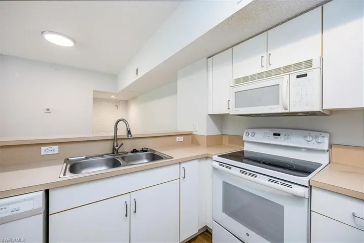 Kitchen featuring white cabinets, white appliances, and sink