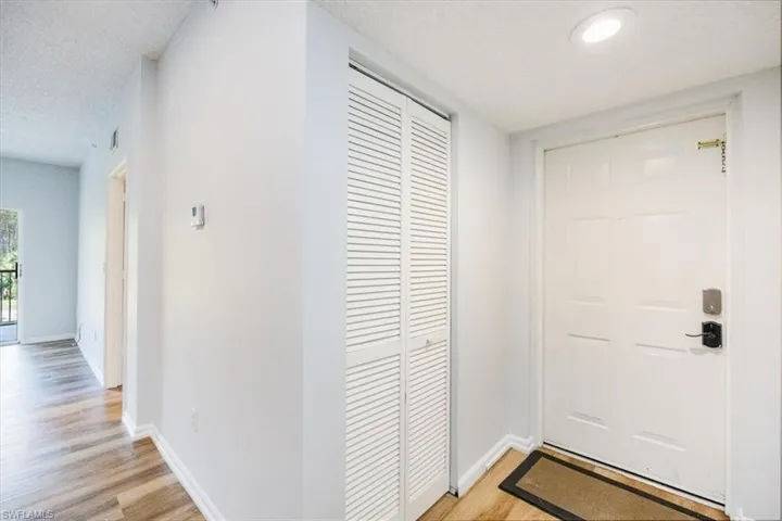 Hall with a textured ceiling and light hardwood / wood-style floors
