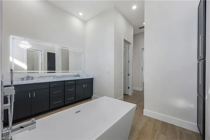 Bathroom with a soaking tub, double vanity, a sink, and visible vents