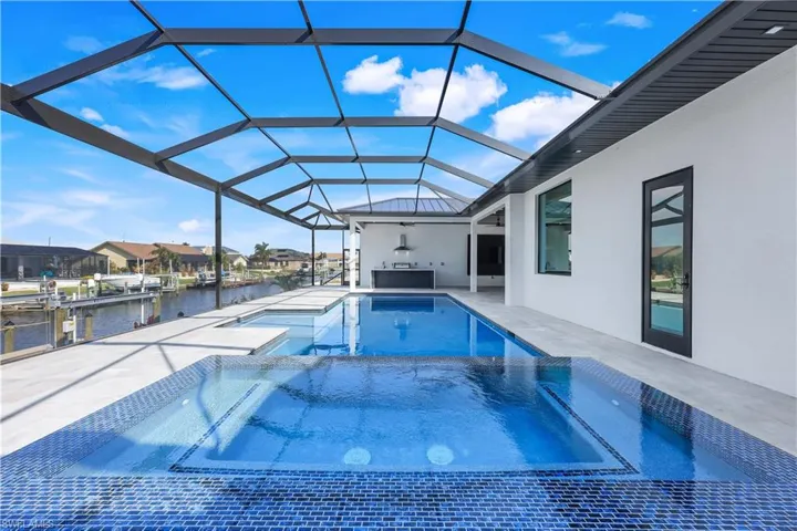 View of swimming pool with a patio, a water view, a pool with connected hot tub, and a lanai