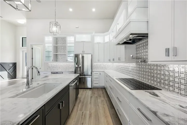 Kitchen featuring white cabinetry, custom range hood, a sink, appliances with stainless steel finishes, and dark cabinets