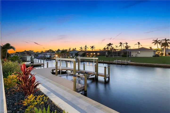Dock area featuring a water view, boat lift, a yard, and a residential view
