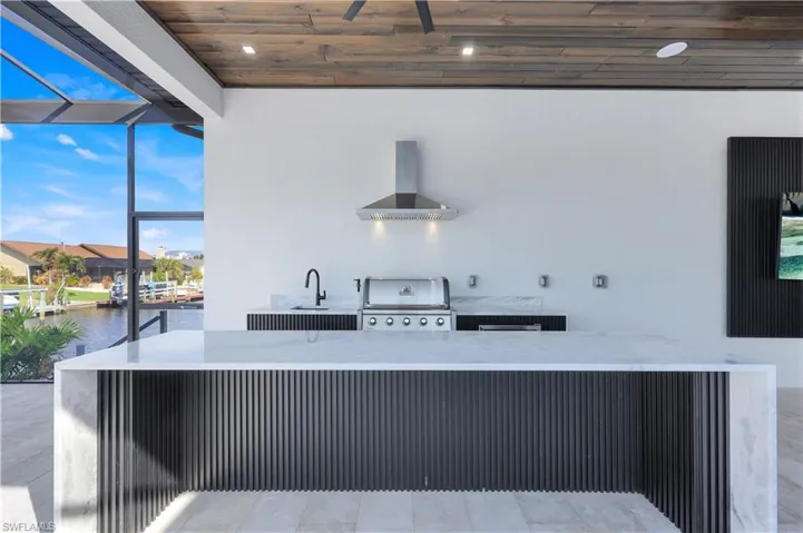 Kitchen with a water view, floor to ceiling windows, wall chimney exhaust hood, a sink, and wood ceiling