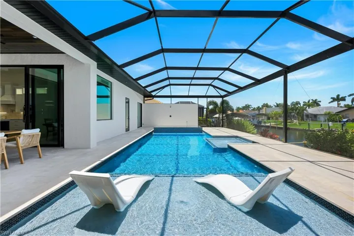 View of pool with a patio area and glass enclosure