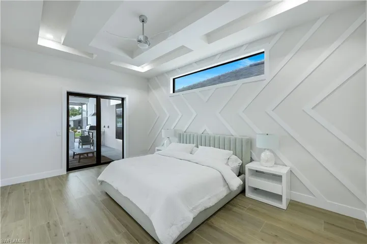 Bedroom featuring access to outside, a ceiling fan, light wood finished floors, and a raised ceiling