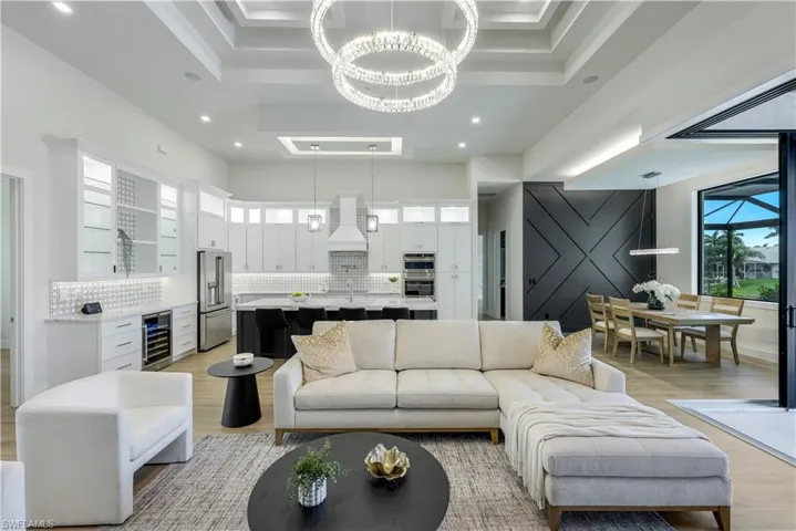 Living area featuring wine cooler, a chandelier, light wood finished floors, recessed lighting, and a raised ceiling