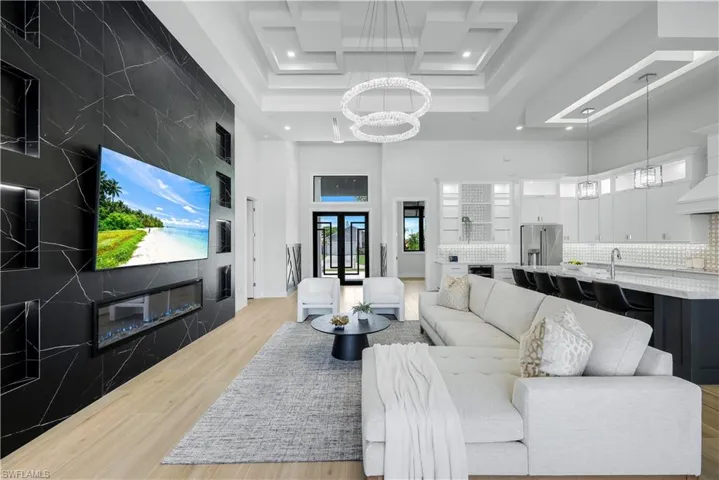 Living room featuring a chandelier, a high ceiling, recessed lighting, light wood finished floors, and healthy amount of natural light