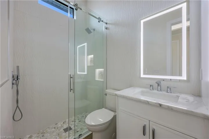 Bathroom with a shower stall, toilet, and vanity