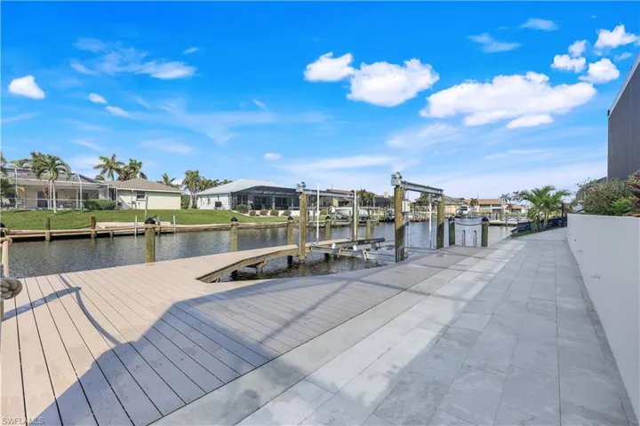 View of dock with a water view, boat lift, and a residential view