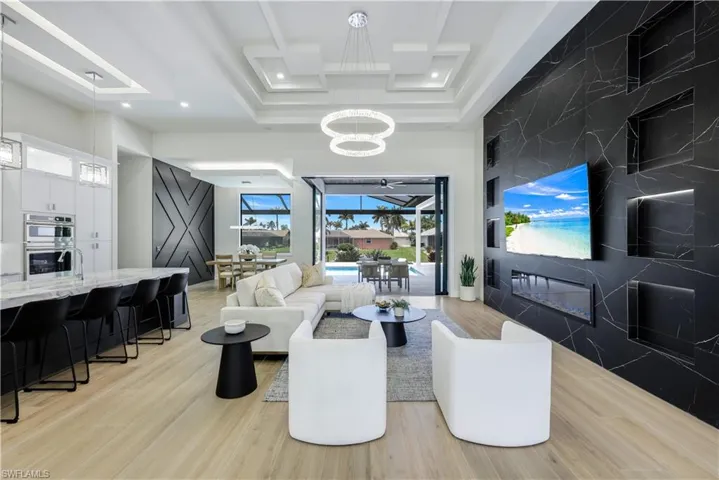 Living area with a chandelier, coffered ceiling, recessed lighting, light wood-style floors, and a towering ceiling
