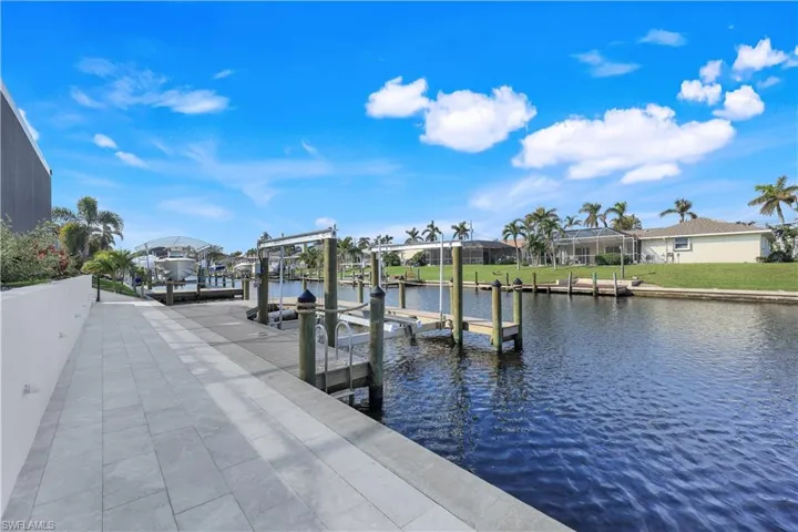 Dock area featuring a lawn, a water view, boat lift, and a residential view