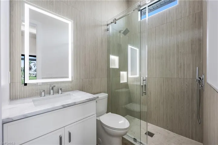 Full bathroom featuring a stall shower, tile walls, toilet, and vanity