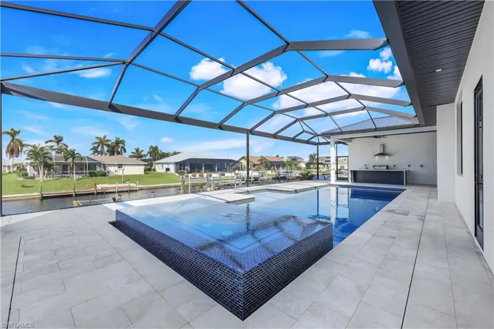 View of swimming pool featuring a patio area, an outdoor kitchen, a lanai, and a residential view