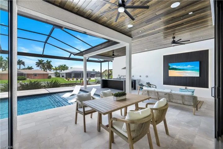 View of patio with a ceiling fan, an outdoor pool, glass enclosure, outdoor dining space, and a residential view